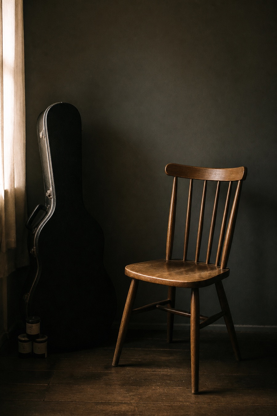 Empty chair beside a guitar case in a dim room